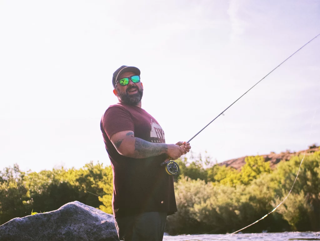 Man in red tank top holding fishing rod photo, Fishing in Idaho